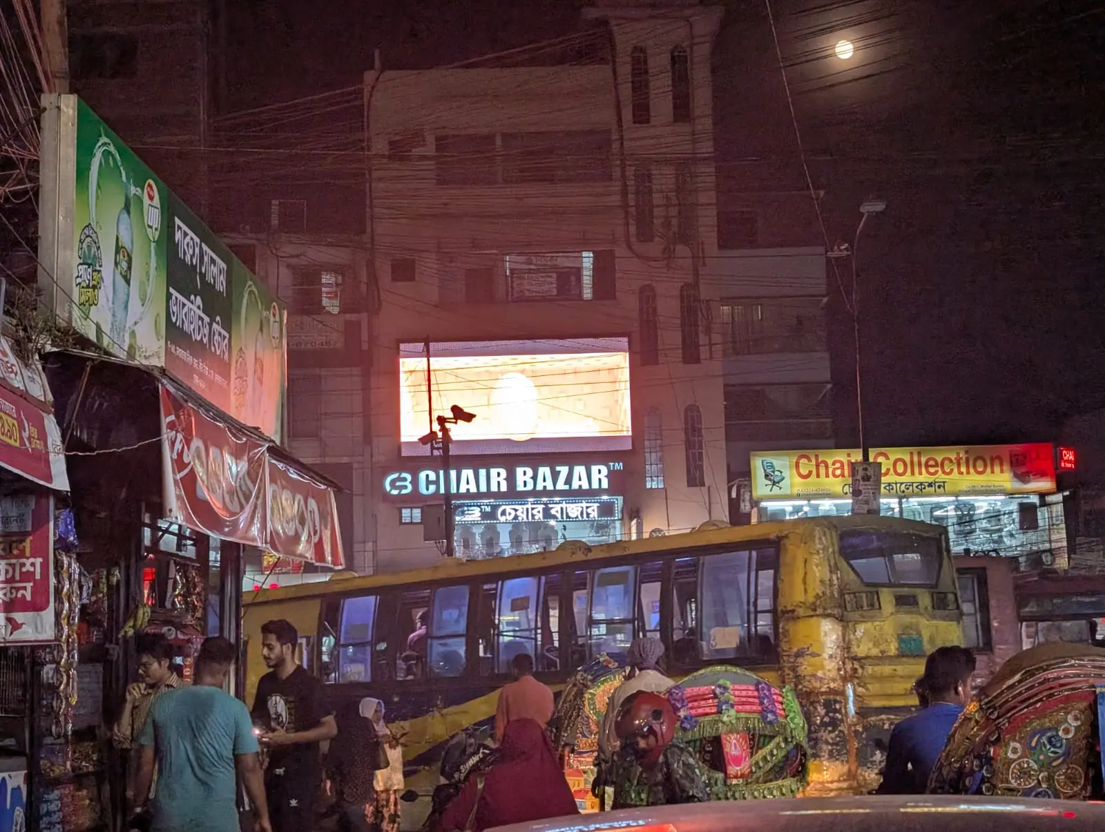 LED screen above a packed Dhaka street at night